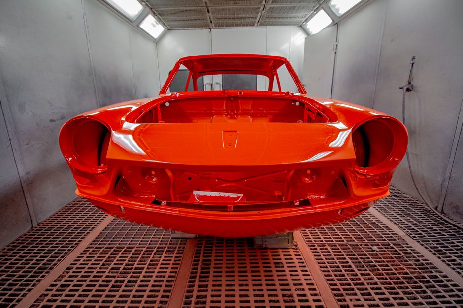 Vividly painted car body in a professional industrial spray paint booth.
